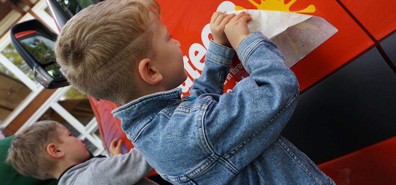 Soziales Engagement von mateco: 2 Kindergartenkinder bekleben eine rote Arbeitsbühne