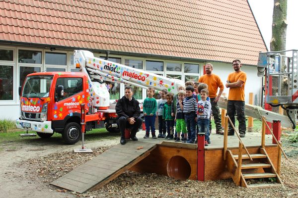 Soziales Engagement von mateco in Mutterstadt: Baumpfleger, mateco-Arbeitsbühne und Kindergartenkinder posieren für ein Gruppenbild im Garten