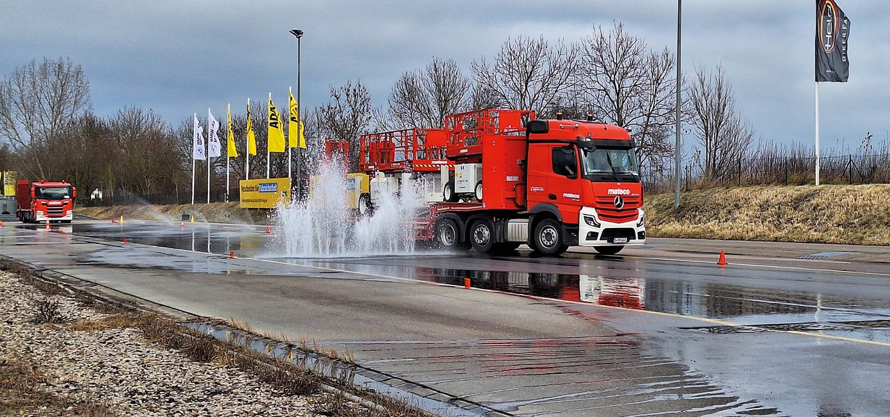 Rote LKW-Arbeitsbühne fährt über eine Pfütze