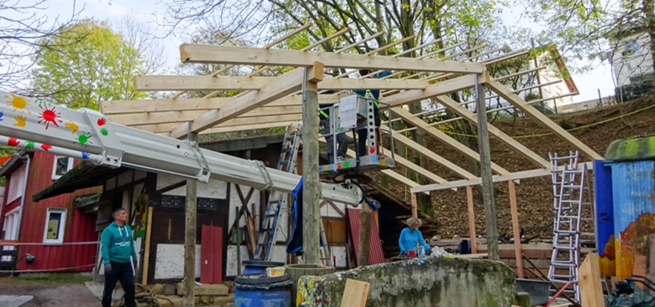 mateco unterstützt den Abenteuerspielplatz: Zwei Männer befestigen ein Holzvordach mit einer Bohrmaschine