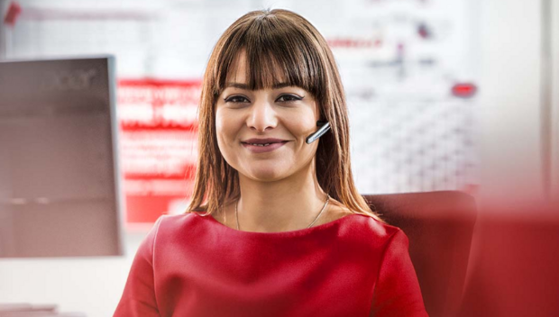 Mitarbeiterin sitzt am Tisch und telefoniert mit ihren Headsets