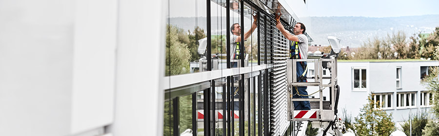 Arbeiter steht auf einer Arbeitsbühne und putzt die Fenster